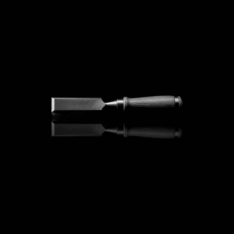 Ciseau à bois au manche de bois, posé sur un miroir noir qui le reflète