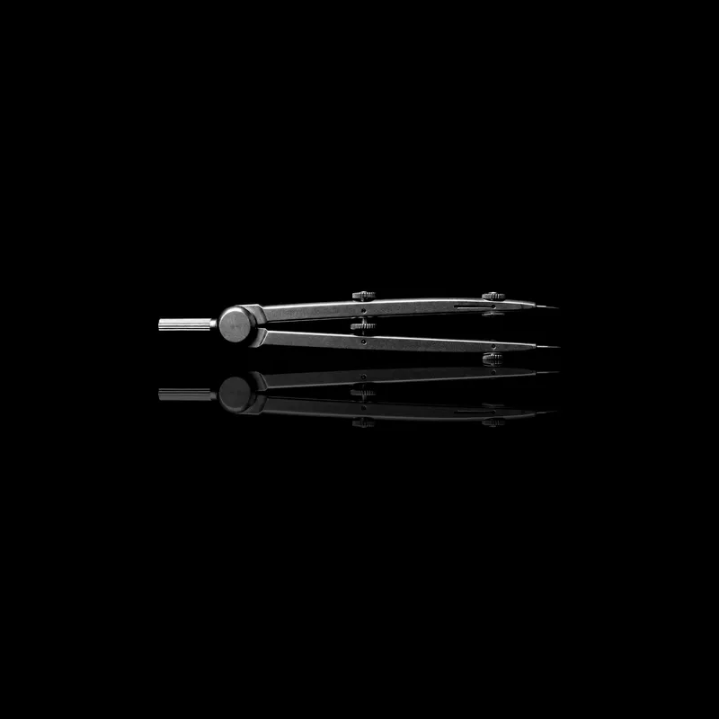 Compas de dessin en acier, posé sur un miroir noir qui le reflète