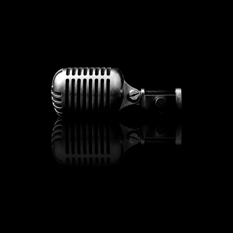 Micro de scène à grille chromée, posé sur un miroir noir qui le reflète
