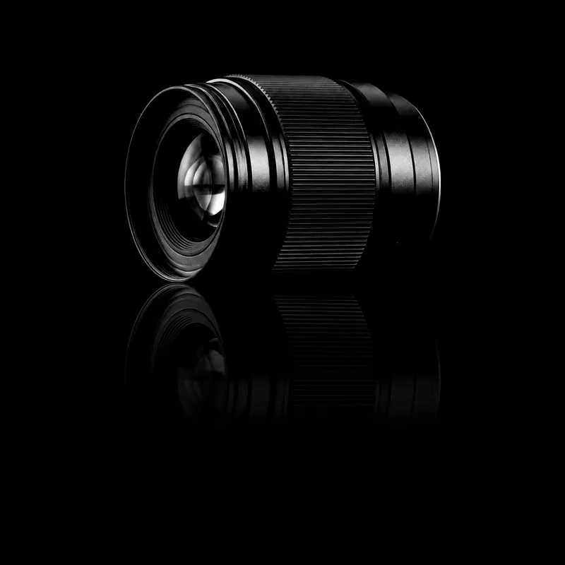 Objectif photo, posé sur un miroir noir qui le reflète